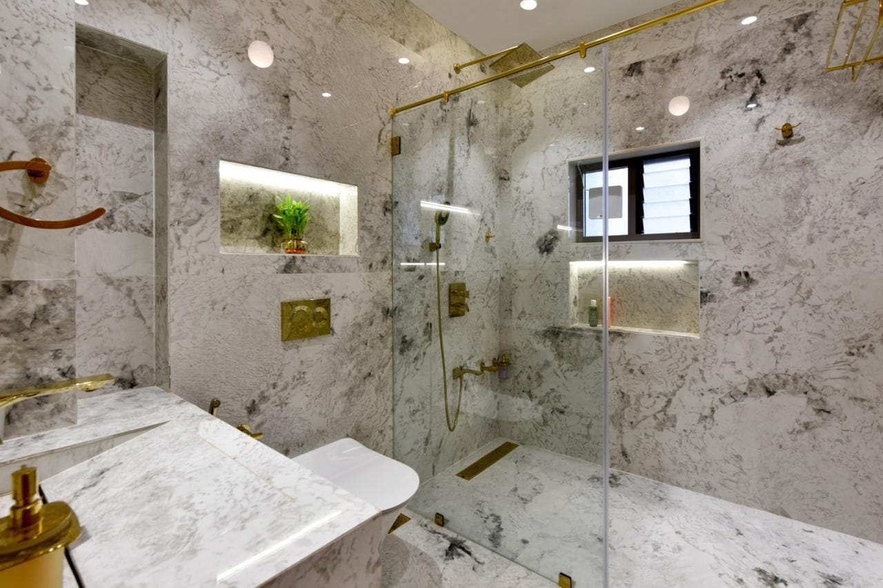Marble bathroom with brass fixtures and glass shower