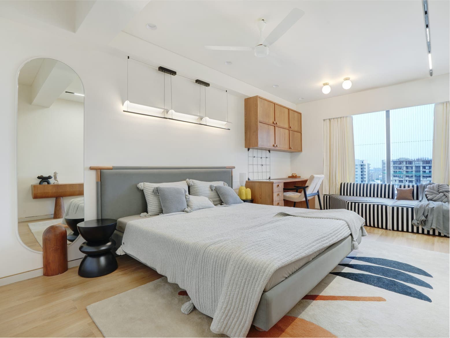 Guest bedroom with grey bed, striped day sofa and teak cabinets