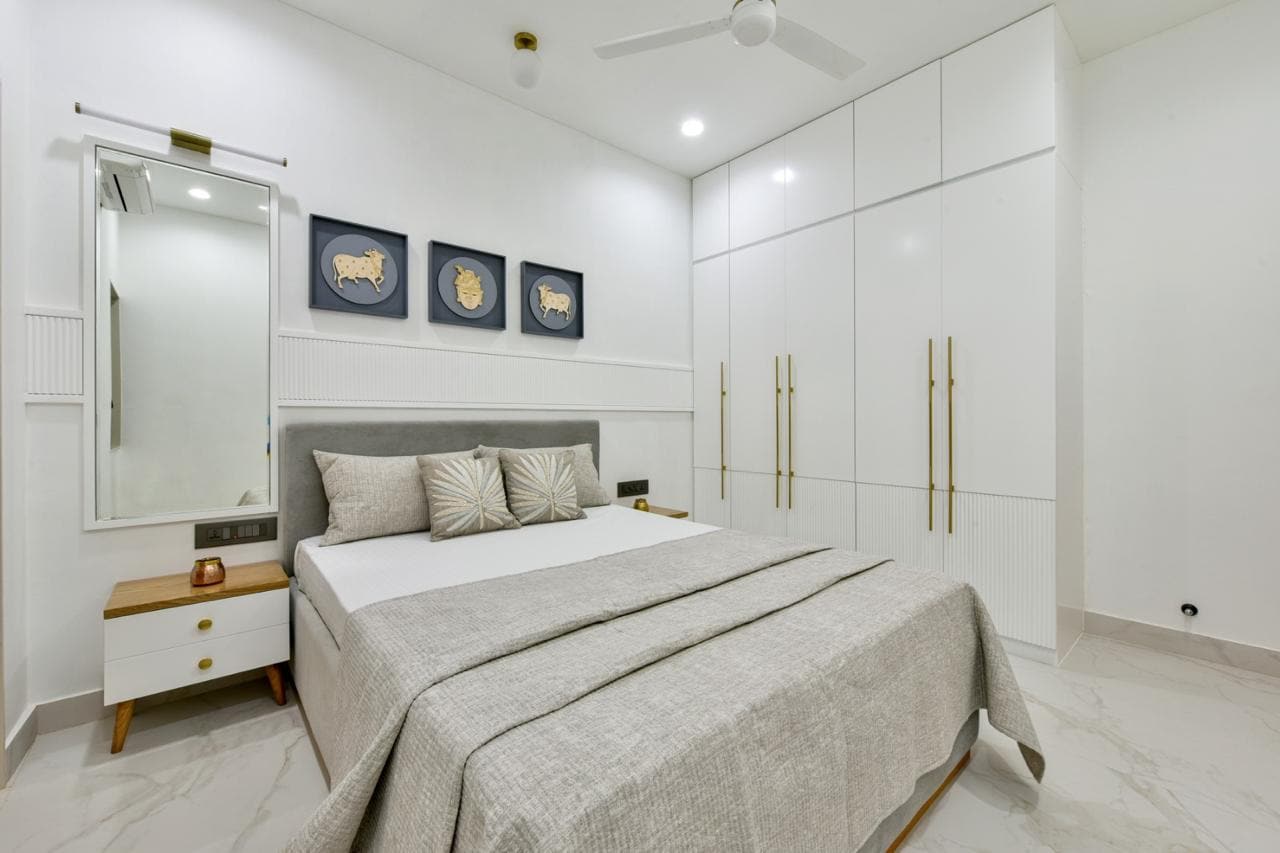 Bedroom with white panelled wardrobe wall and art
