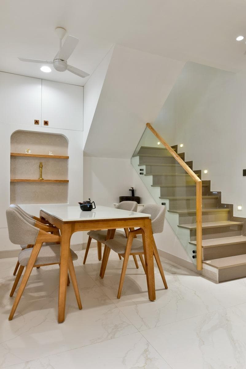 Dining table beside glass-railed duplex staircase