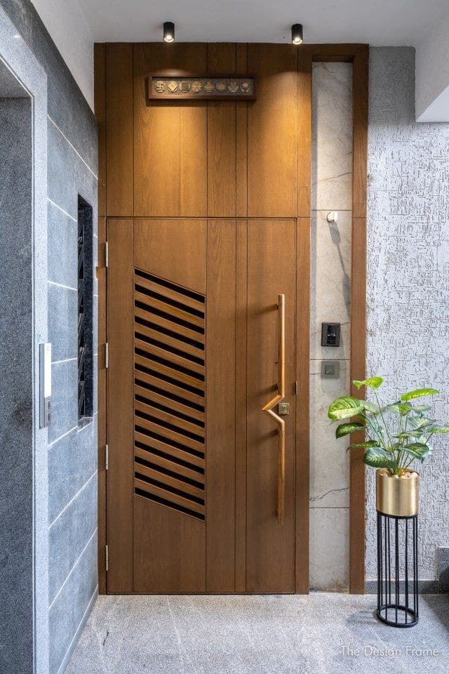 Louvered teak main door beside granite feature wall