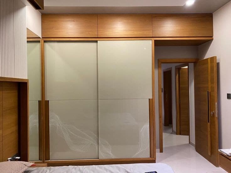 Cream glass sliding wardrobe along bedroom corridor